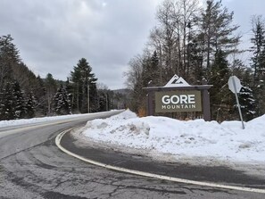 A road curving to the right with a snow-covered landscape and a sign for Gore Mountain.