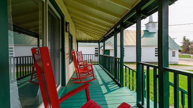 A porch with green railings and red rocking chairs.