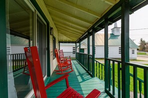 Une véranda avec des balustrades vertes et des fauteuils à bascule rouges.