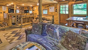 Ein gemütliches Blockhaus-Interieur mit rustikalen Holzeinrichtungen, einem Kamin, einer Couch mit Tiermotiven und einer Bar.