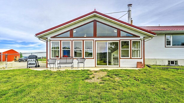 A two-story house with a large front porch, a garage, and a backyard with a grill. - Stunning Wisconsin Retreat on Active Farm! (Arena)