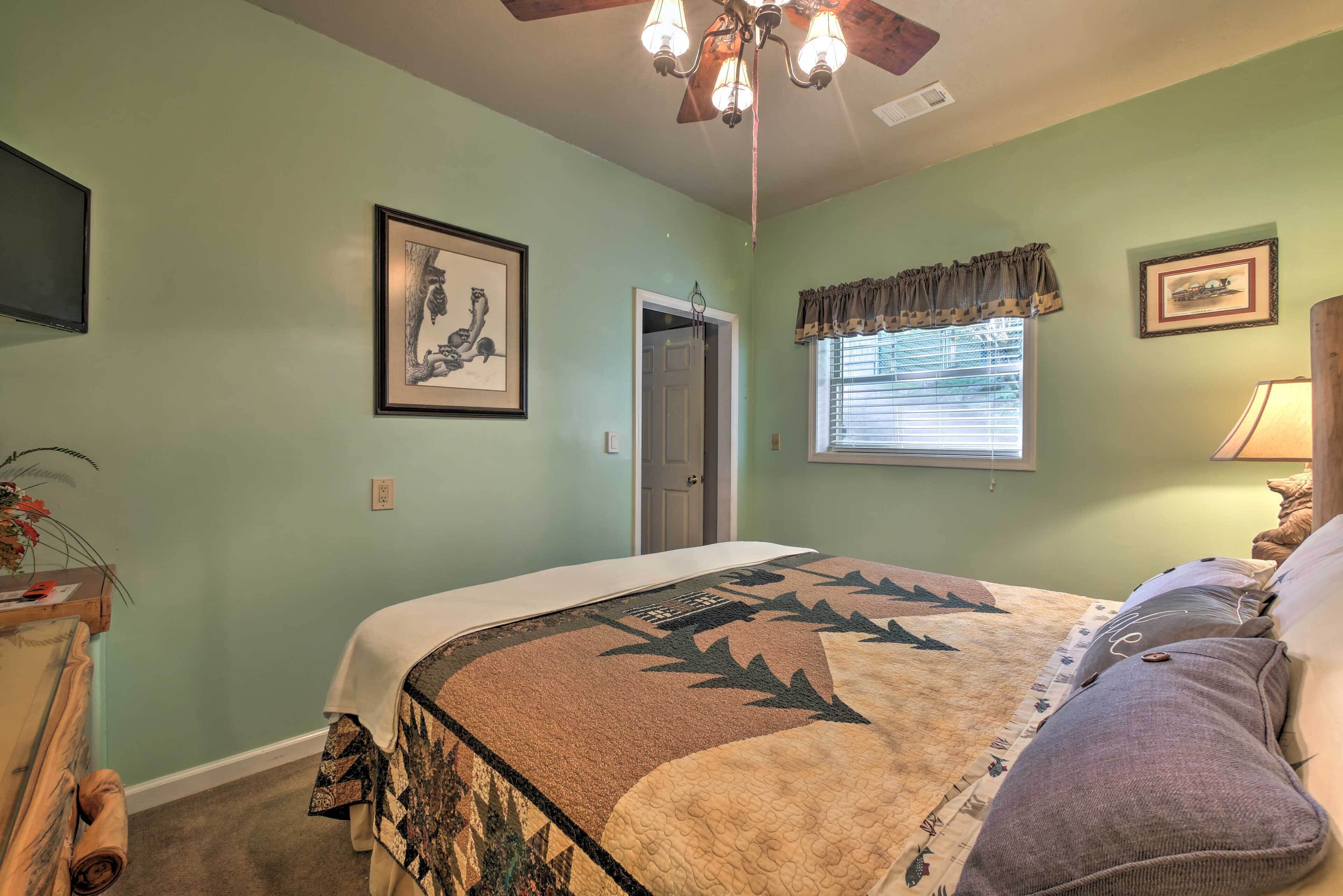 A bedroom with a bed, a ceiling fan, a window with blinds, and framed pictures on the wall.