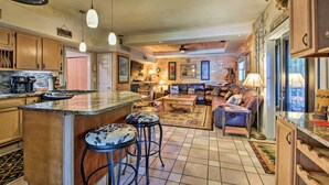 A spacious kitchen with wooden cabinets, a large island with stools, and a dining area with a sofa and coffee table. - Tenn River Cabin w/ Hot Tub - 10 Mi to Chattanooga (Chattanooga)