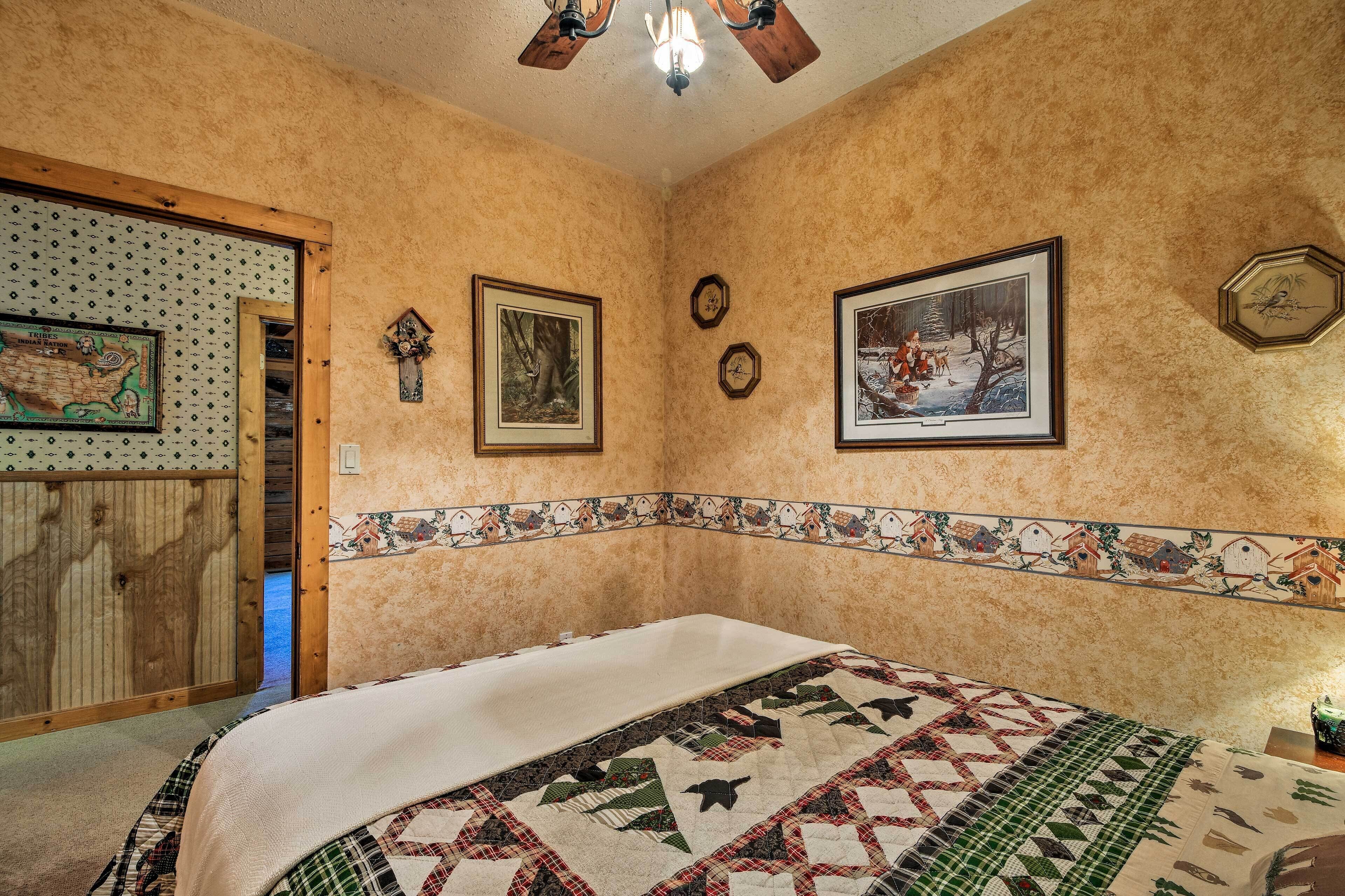 A bedroom with a large bed, a wooden door, and a wall with framed pictures and clocks.
