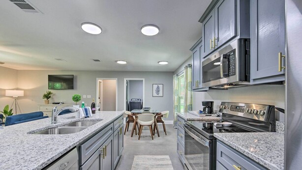 A modern kitchen with granite countertops, stainless steel appliances, and a dining area with a table and chairs.