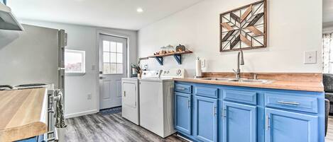 Une cuisine moderne avec des armoires bleues, un plan de travail en bois et un lave-linge encastré.