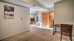 A hallway with a poster, a wooden door, a table, and a chair.