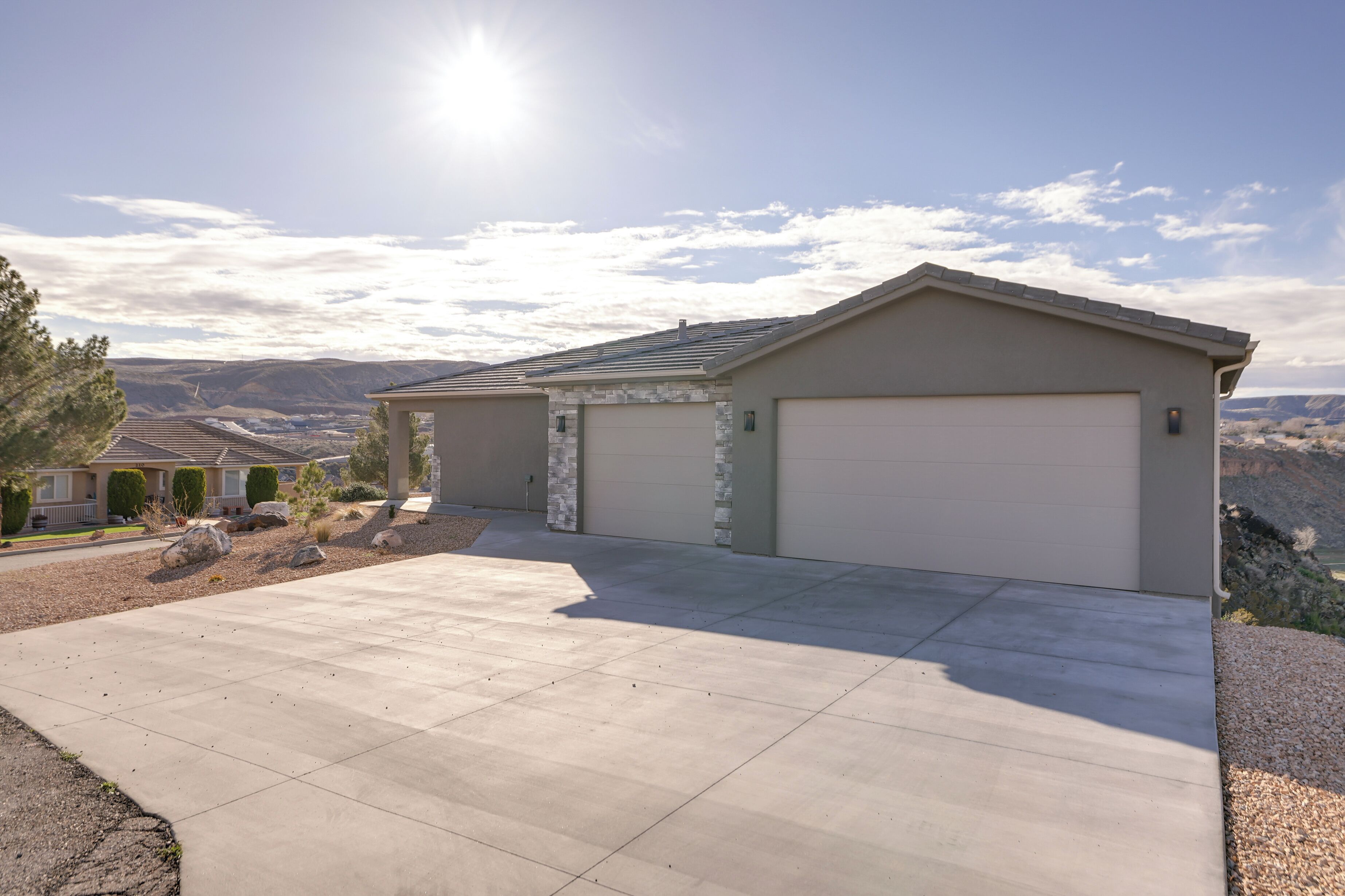 Une maison de plain-pied avec un garage, une allée et une vue sur les montagnes en arrière-plan.