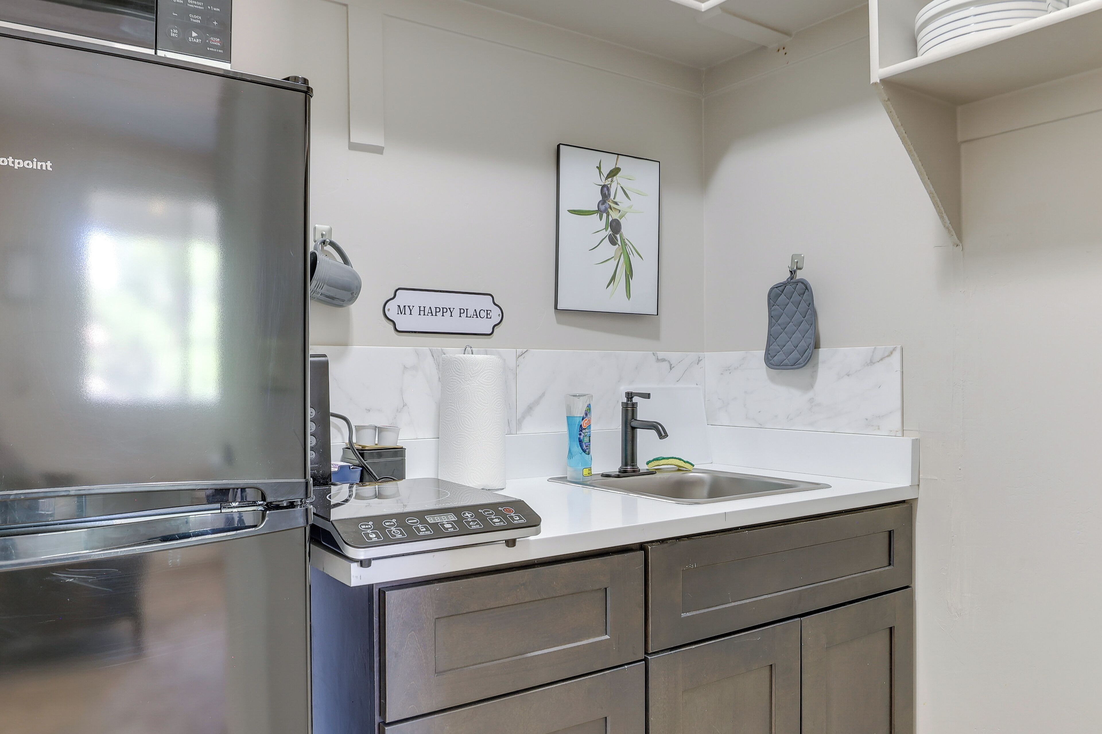 A modern kitchen with a stainless steel refrigerator, a built-in coffee maker, a sink, and a countertop with a dish rack.