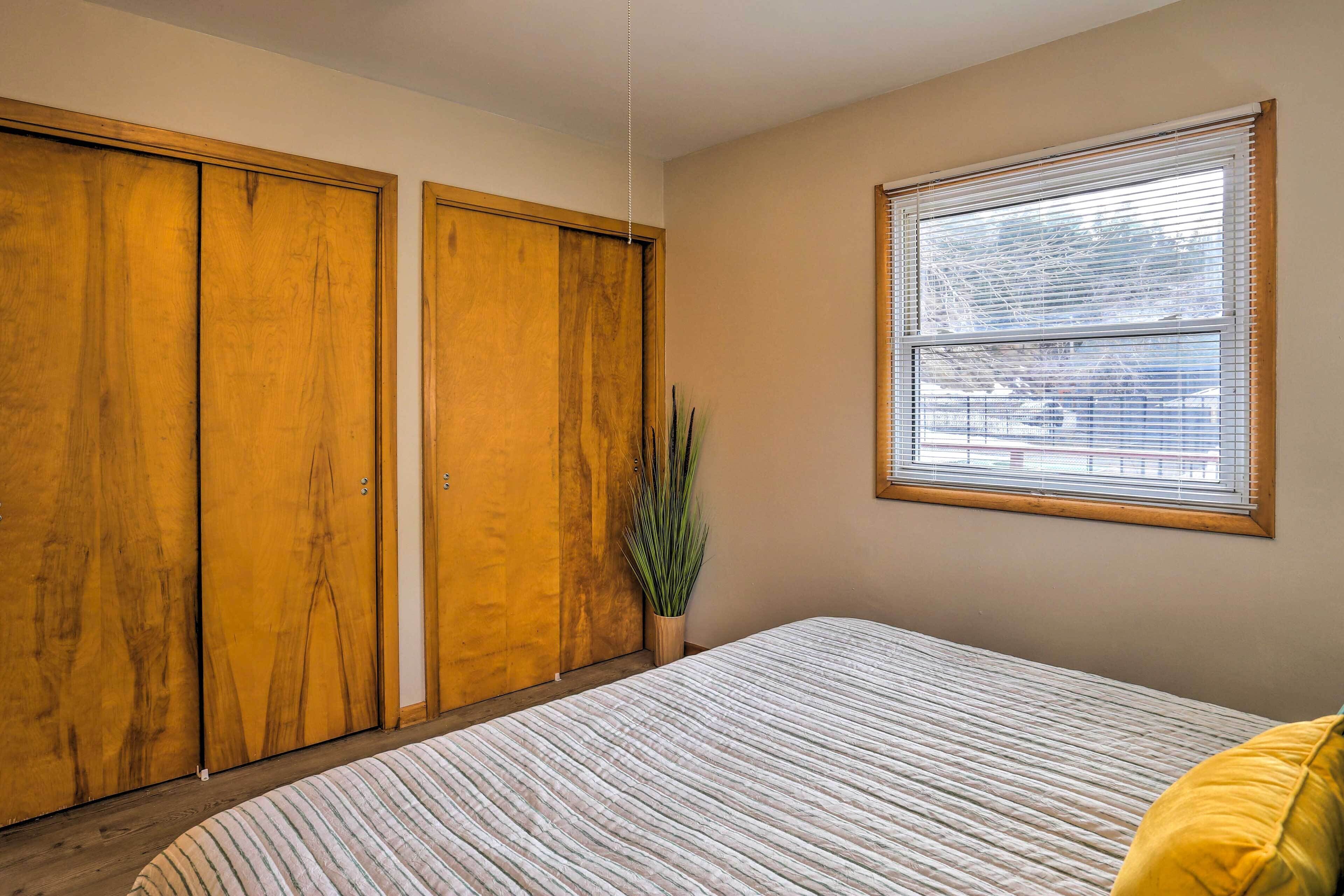 Un dormitorio con cama, armario de madera y ventana con persianas.