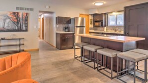 A modern kitchen with a central island, bar stools, and a refrigerator.