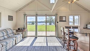 A spacious living area with a large sliding glass door leading to a patio, a sofa, a dining table with chairs, and a ceiling fan. - Waterfront Butternut Lake Getaway w/ Private Dock! (Butternut)