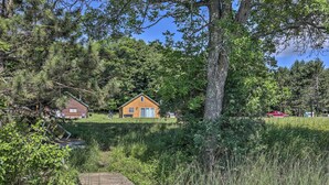 A wooden cabin with a small porch, surrounded by dense forest and a clear sky. - Waterfront Butternut Lake Getaway w/ Private Dock! (Butternut)