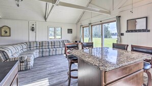A spacious living area with a large sectional sofa, a kitchen with granite countertops, and large windows offering a view of the outdoors. - Waterfront Butternut Lake Getaway w/ Private Dock! (Butternut)