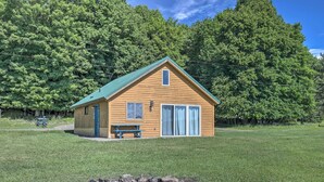 A wooden cabin with a green roof, a bench, and a fire pit in front. - Waterfront Butternut Lake Getaway w/ Private Dock! (Butternut)