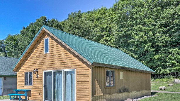 A wooden cabin with a green roof, a sliding glass door, and a picnic table. - Waterfront Butternut Lake Getaway w/ Private Dock! (Butternut)