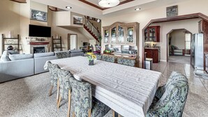 Un salon spacieux avec une grande table à manger, un canapé et un escalier menant à un autre niveau.