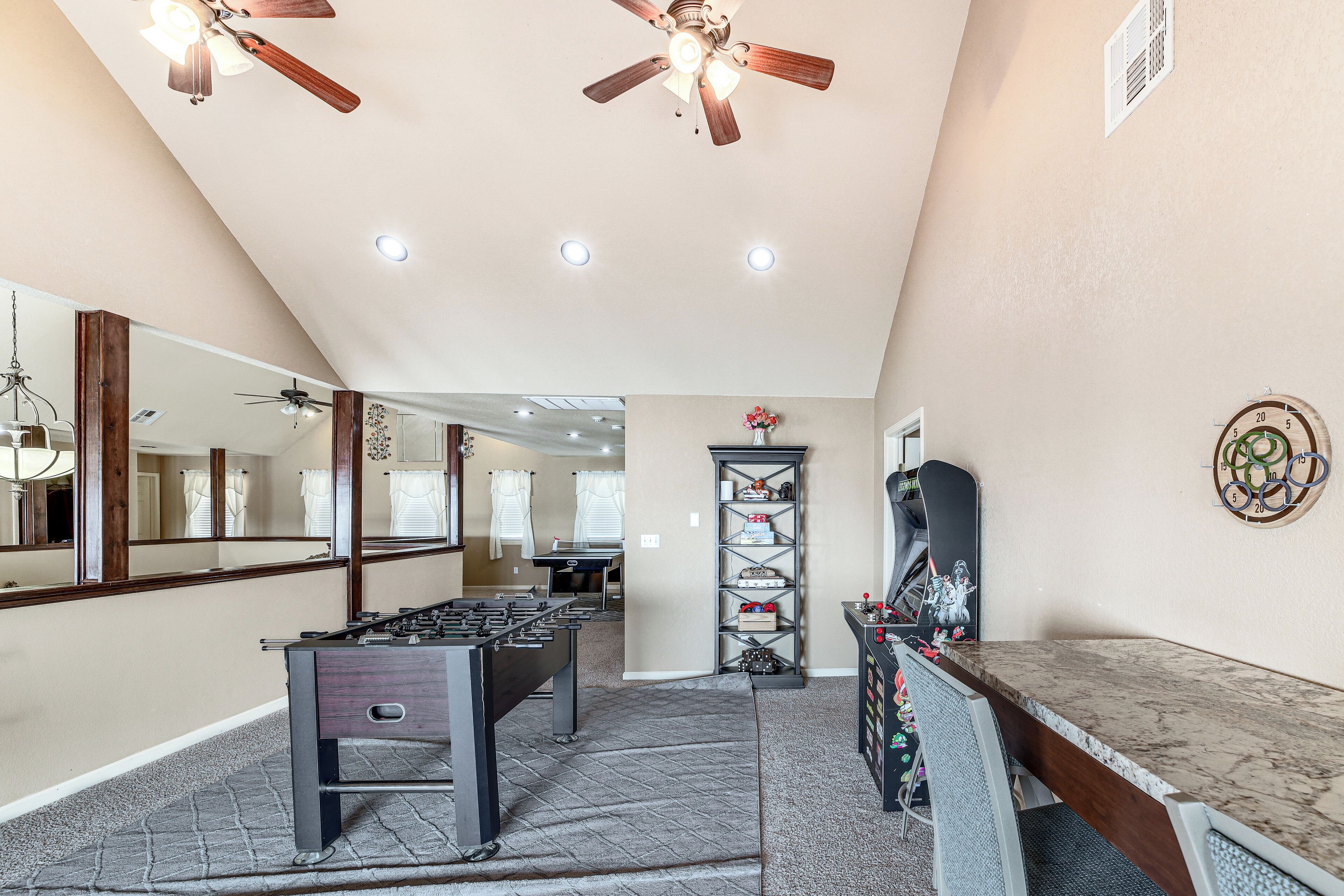 A spacious room with a foosball table, ceiling fans, and a large mirror.