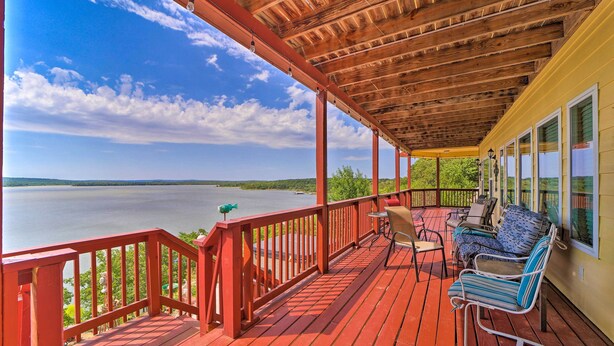 Une terrasse en bois avec une rambarde rouge donnant sur un lac.