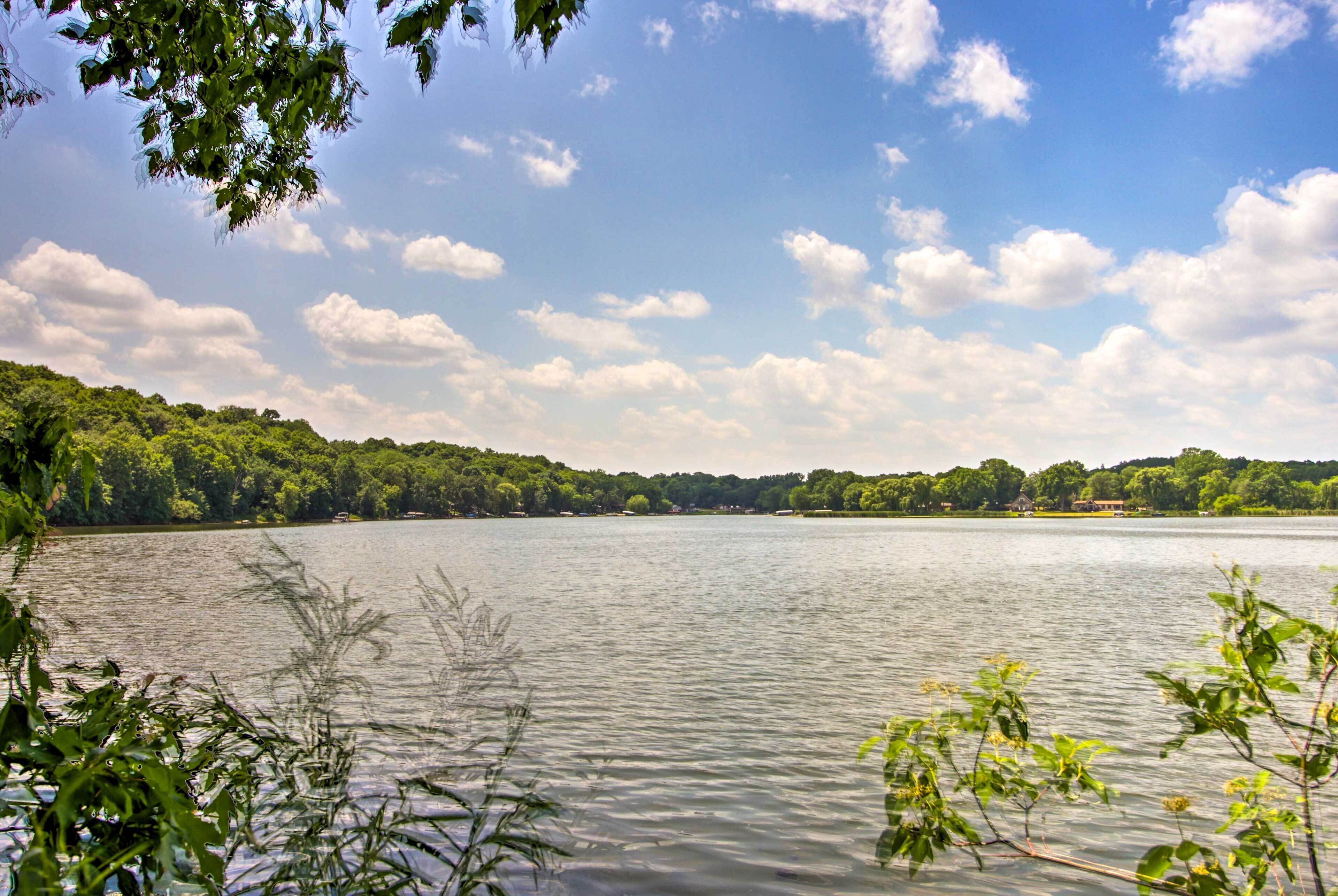 A lake with a forested shoreline and a clear sky.
