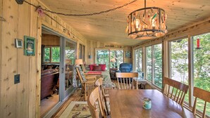 A cozy cabin interior with a wooden dining table, chairs, and a chandelier. - Year-round Waterfront Getaway: Lake Access + Dock! (South Haven)