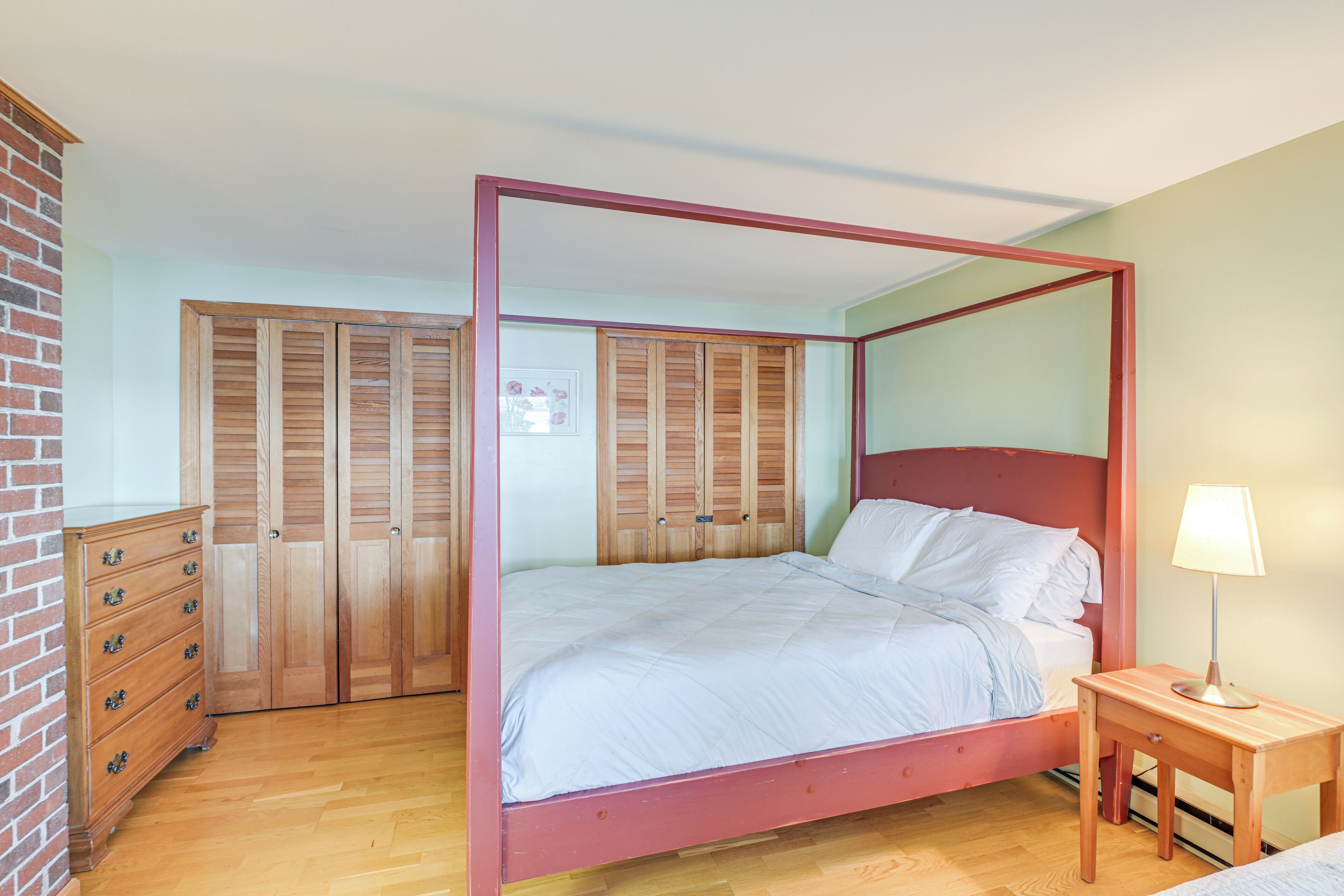 A four-poster bed with a wooden frame and a nightstand with a lamp.