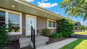 A residential house with a front porch, a door, and a small staircase. - Winona Lake Access With Pier (Warsaw)