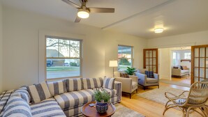 A modern living room with a sectional sofa, a small table with a plant, and a wicker chair. - Indiana Vacation Rental - Walk to Syracuse Lake! (Syracuse)