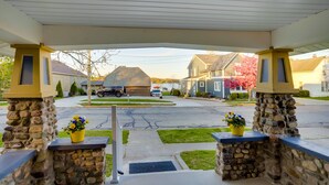 A covered entrance with stone pillars, a driveway, and houses in the background. - Indiana Vacation Rental - Walk to Syracuse Lake! (Syracuse)