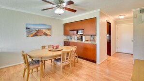 A dining area with a wooden table and chairs, a ceiling fan, and a kitchen area with a countertop and cabinets. - Florida Getaway - Balconies, Grill & Near Beaches! (Daytona Beach)