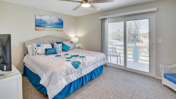 A bedroom with a bed, a ceiling fan, a large window, and a view of the outdoors. - Florida Getaway - Balconies, Grill & Near Beaches! (Daytona Beach)