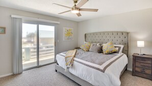 A bedroom with a large bed, a ceiling fan, a sliding glass door, and a nightstand with a lamp. - Florida Getaway - Balconies, Grill & Near Beaches! (Daytona Beach)