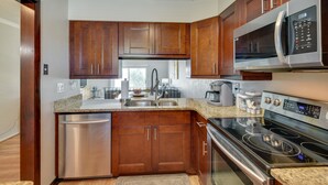 A modern kitchen with wooden cabinets, stainless steel appliances, and granite countertops. - Florida Getaway - Balconies, Grill & Near Beaches! (Daytona Beach)