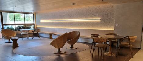 A modern interior with wicker furniture, a wooden ceiling, and a wall-mounted light feature.