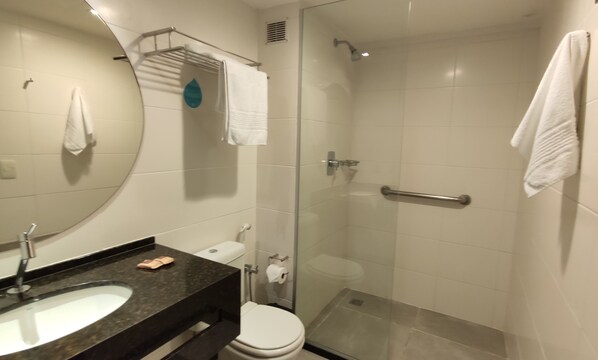 A bathroom with a sink, toilet, and glass-enclosed shower stall. - Flat Frente Mar R206 (Maceió)