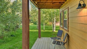 A wooden deck with a pergola, a chair, and a wall-mounted light fixture. - Near Skiing & Hiking: Inviting Retreat in Victor! (Victor)