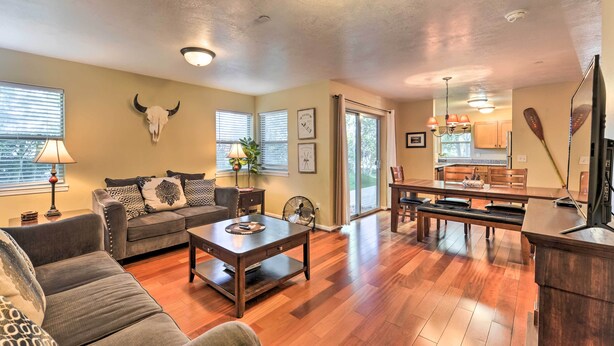 A spacious living room with a sofa, coffee table, and dining area. There is a bull skull on the wall and a large window providing natural light. - Near Skiing & Hiking: Inviting Retreat in Victor! (Victor)