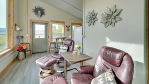 Ein geräumiges Wohnzimmer mit einer großen Ledersofa, einem Holztisch und Blick ins Freie durch eine Tür.
