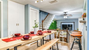 Een moderne keuken met een houten eettafel, een trap naar een woonruimte en een televisie op de achtergrond.