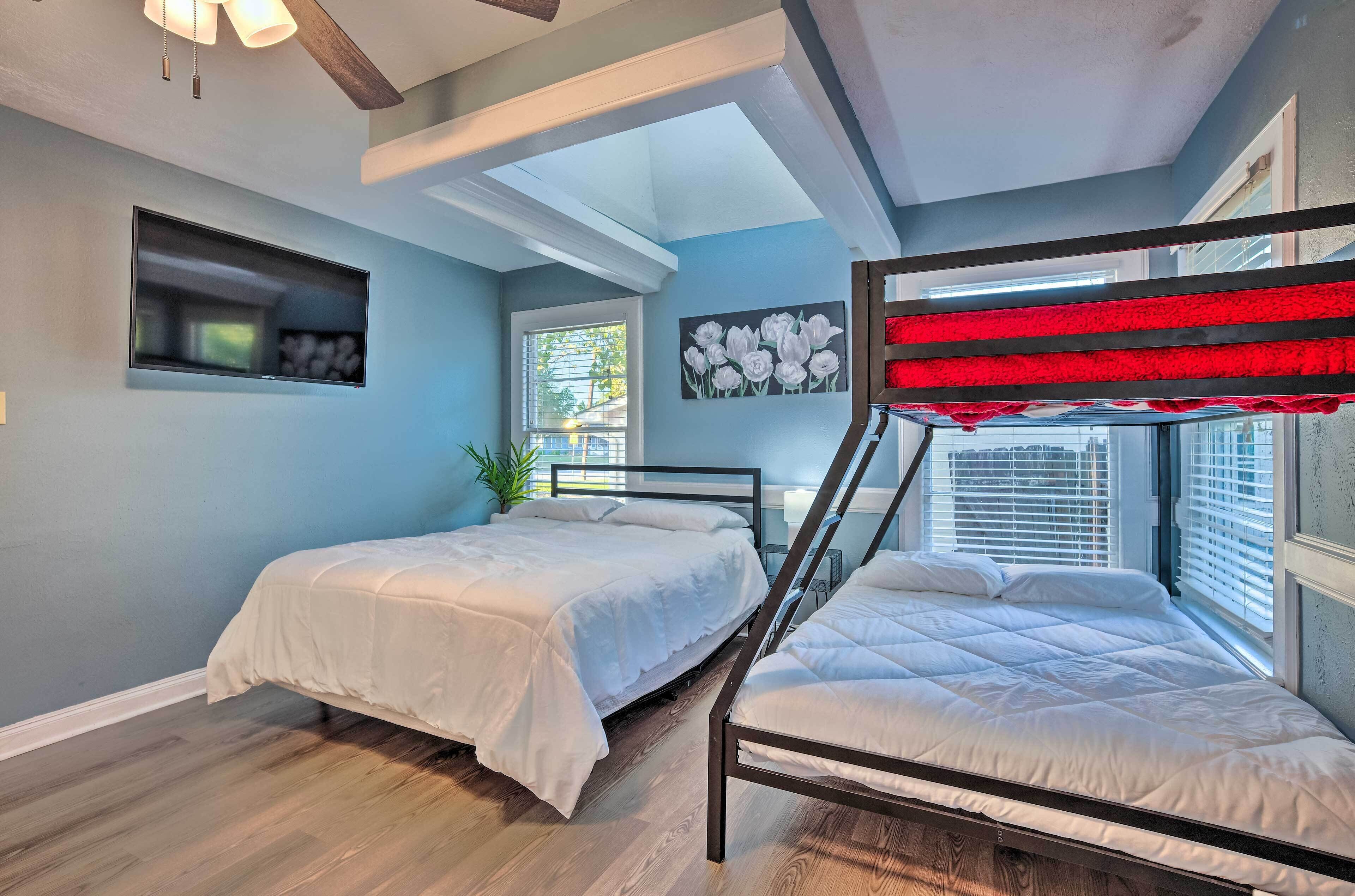 Un dormitorio con dos camas, ventilador de techo, televisión y ventana con persianas.