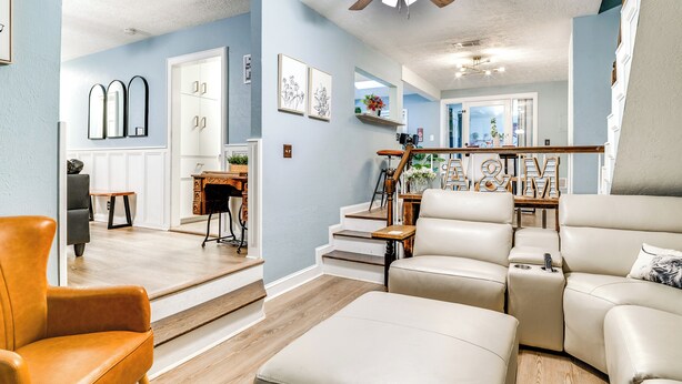 Een moderne woonkamer met een modulaire bank, een houten salontafel en een plafondventilator.