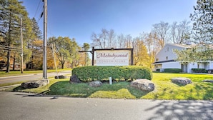 Segnaletica per il condominio Melodywood, con un prato curato e grandi massi.