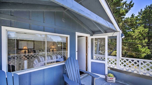 Ein blaues Gebäude mit einer überdachten Veranda, einem roten Adirondack-Sessel und einem kleinen Blumentopf.