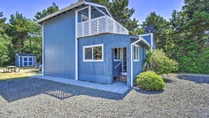 Eine blaue Holzhütte mit Balkon, eine kleine Werkstatt und ein Picknicktisch im Hintergrund.