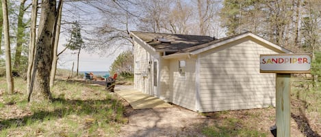 A small, single-story cabin with a wooden deck and a sign reading "SANDPIPER."
