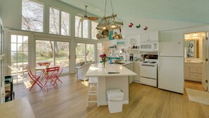 A spacious kitchen with a large island, white cabinetry, and a view through large windows. - Beachfront Lake Michigan Cottage: Fire Pit & Deck (Muskegon)
