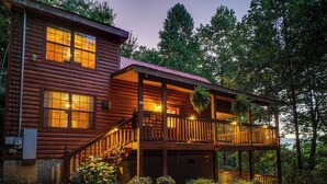 A two-story log cabin with a balcony, surrounded by trees. - Bear Mountain Chalet in the Woods w/ Hot Tub (Sevierville)