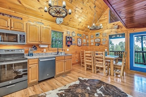 A log cabin interior with wooden walls, a kitchen with modern appliances, and a dining area with wooden furniture.