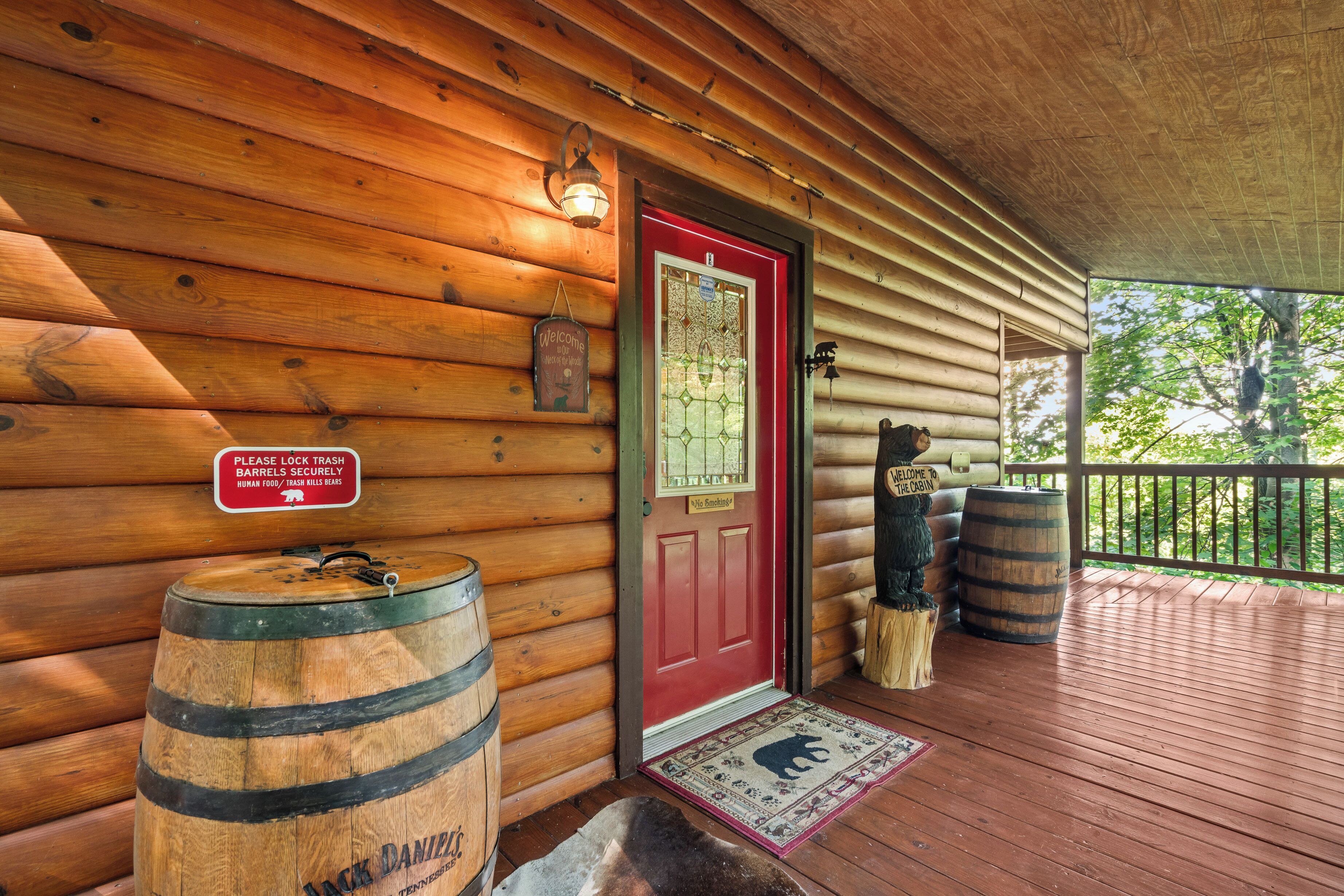 A wooden cabin with a red door, a welcome sign, and a bear symbol on the doormat.
