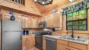 A modern kitchen with wooden cabinets, stainless steel appliances, and a granite countertop. - Bear Mountain Chalet in the Woods w/ Hot Tub (Sevierville)
